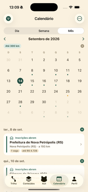 Calendário mensal do Aulias com abas Dia, Semana e Mês, o filtro de até 300 km e os dias marcados por pontos coloridos.